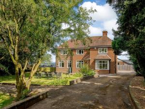 a brick house with a tree in the driveway at Renchers Farmhouse in Crossway Green