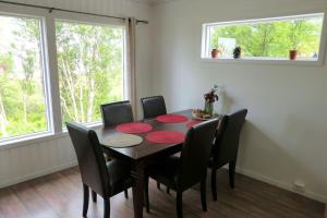 a dining room with a table and chairs and two windows at Cozy Apartment between sea and mountains in Mefjordvær +28 photos
