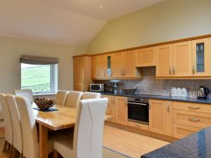 a kitchen with wooden cabinets and a wooden table and chairs at Belah Barn in Kirkby Stephen