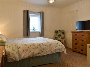 a bedroom with a bed and a television and a chair at Belah Barn in Kirkby Stephen