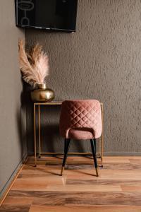 una sedia rosa seduta accanto a un tavolo con un vaso di Hotel La Casa a Valkenburg