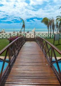 a wooden walkway leading to a beach with palm trees at ECO FLECHEIRAS RESIDENCE in Trairi