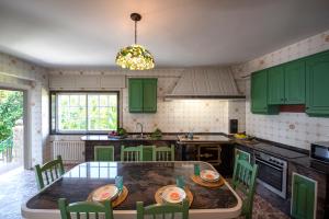 a kitchen with green cabinets and a table with chairs at Luxury Singular Villa Rosa in Padrón