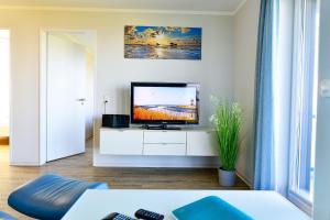 a living room with a flat screen tv on a white cabinet at Beach Lodge BL03 in Cuxhaven