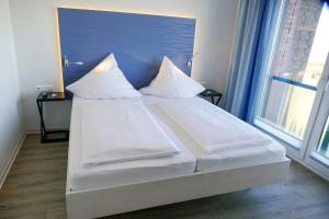 een bed met witte lakens en kussens in een kamer bij Beach Lodge BL03 in Cuxhaven
