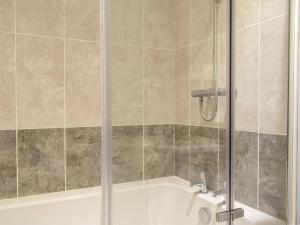 a shower with a glass door next to a bath tub at Windhover in Glasbury