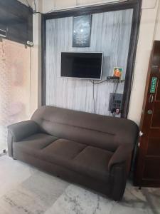 een bruine bank in een woonkamer met een flatscreen-tv bij HOTEL ROYALE in Calcutta