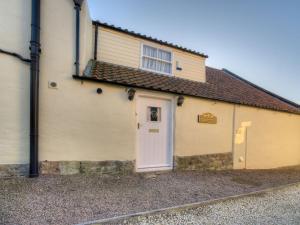 a yellow building with a white door and a window at Kings Head Cottage in Pickering