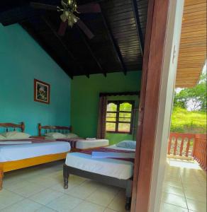 a bedroom with three beds in a room with green walls at Hotel Rosalila in Copan Ruinas