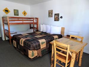 a bedroom with a bed and a table and a bunk bed at Eagle's Nest Motel in Priest River
