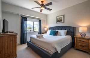 a bedroom with a bed with a ceiling fan and a window at Downunder Mountain Retreat by Revelstoke Vacations in Revelstoke