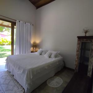 a bedroom with a white bed and a window at Pé na Areia - Pousada in Barra Grande