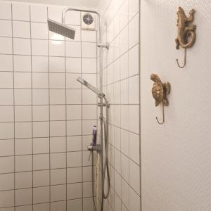 a shower in a bathroom with white tiles at Vanneberga gamla skola in Fjälkinge