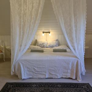 a bedroom with a white bed with curtains at Vanneberga gamla skola in Fjälkinge