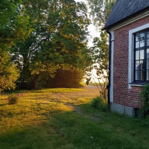 una vecchia casa in mattoni con un campo e alberi di Vanneberga gamla skola a Fjälkinge