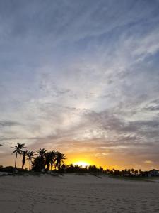 een zonsondergang op een zandstrand met palmbomen bij Apartamento na Praia de Iracema, Meireles. in Fortaleza