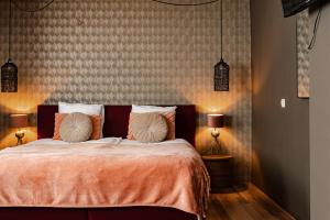 a bedroom with a bed with orange sheets and two lamps at Hotel La Casa in Valkenburg