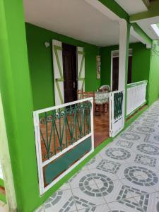 a green house with a balcony with a tile floor at F3 paisible in Capesterre-Belle-Eau