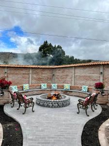 two benches and a fire pit in a yard at Hacienda Santa Ana Lodging in Guamote
