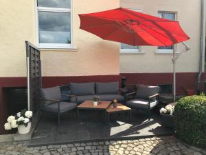 einen roten Regenschirm und einige Stühle sowie einen Tisch und Stühle in der Unterkunft APARTMENT SONNE Reusa in Plauen