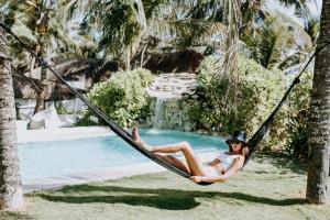 a woman laying in a hammock next to a pool at Coco Unlimited in Tulum