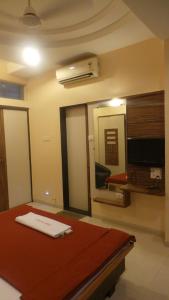 Zimmer mit einem Bett, einem TV und einem Spiegel in der Unterkunft Hotel Royal Residency Executive in Miraj