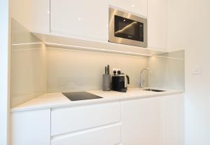 eine Küche mit weißen Schränken und einem Waschbecken in der Unterkunft Sale Place Serviced Apartments by Concept Apartments in London