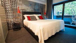 a bedroom with a large bed with white sheets and red pillows at Hills Hotel Lisboa in Lisbon