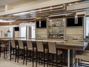 a bar in a restaurant with chairs and a bar counter at Holiday Inn Greensboro Coliseum, an IHG Hotel in Greensboro