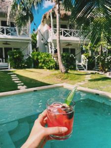 a person holding a drink in front of a swimming pool at Coco Unlimited in Tulum
