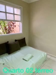Cama blanca en habitación con ventana en Casa Maravilhosa com 6 quartos na Praia Grande - Arraial do Cabo, en Arraial do Cabo