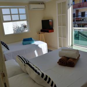 Habitación con cama, TV y sofá. en Casa Maravilhosa com 6 quartos na Praia Grande - Arraial do Cabo, en Arraial do Cabo