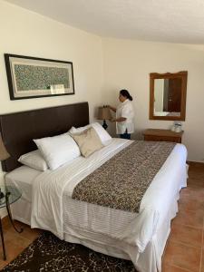 a woman standing in a bedroom with a large bed at Hotel Balneario Tzindejeh in Tasquillo