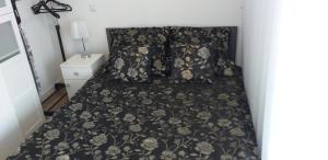 a bed with a black floral bedspread and pillows at Apartament z widokiem Łańcut in Łańcut