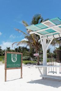 a sign on the beach with a palm tree in the background at Coco Unlimited in Tulum