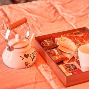 a tea kettle and a tray of food on a bed at Vista Pedra Glamping in Potrerillos