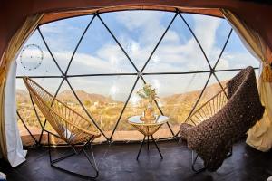 Zimmer mit 2 Stühlen, einem Tisch und einem großen Fenster in der Unterkunft Vista Pedra Glamping in Potrerillos