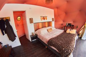 a bedroom with a large bed with an orange wall at Vista Pedra Glamping in Potrerillos