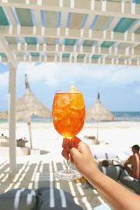 a person holding a glass with an orange in front of the beach at Coco Unlimited in Tulum