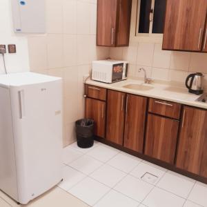 a kitchen with a white refrigerator and a sink at أسفار الأولى للشقق المخدومة in Al Multasa +8 photos