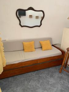 a couch with two yellow pillows and a mirror on the wall at Pequeño y cómodo in Florida