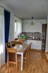 una cocina con mesa y sillas y una cocina con armarios blancos. en Domek u Zbyszka, en Groń