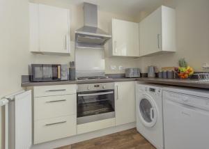 a kitchen with white cabinets and a washer and dryer at Ground Floor Apartment Private Parking Sleeps 5 near City Centre and Shopping Centre in Birmingham