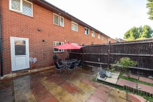 a patio with a table and umbrella in front of a brick building at #Gorgeous 3 beds home#7min to subway, free parking in Thamesmead