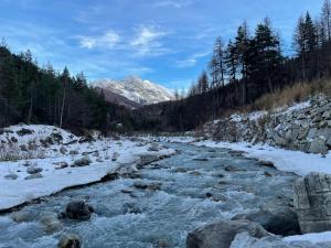 a river with snow on the rocks and trees at Appartamento nel centro storico - Cesana Torinese in Cesana Torinese