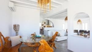 ミコノス・シティにあるUnique Sea View Mykonos Villaのダイニングルーム(ガラスのテーブル、椅子付)