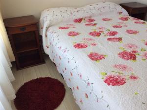 a bed with a white blanket with pink flowers on it at Apartment Concón in Concón