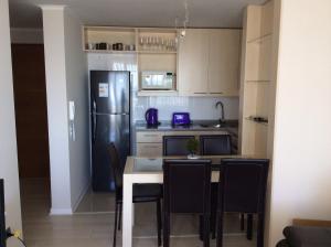 a kitchen with a refrigerator and a table with chairs at Apartment Concón in Concón