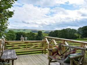 un banco de madera en una terraza con una valla de madera en Hadrians Garden Cottage - Uk3323, en Bardon Mill