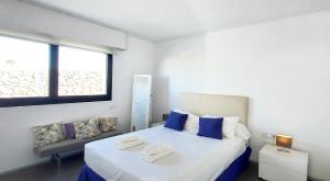 a bedroom with a white bed with blue pillows and a window at Sand Volcano Villa 2 in La Oliva +39 photos